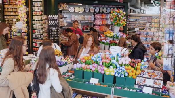 Амстердам, Нидерланды, май 2018 года: много посетителей популярного цветочного рынка в центре Амстердама. Большой выбор цветов и сувениров — стоковое видео