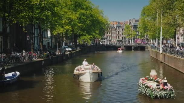 Amesterdam, Německo, květen 2018: Loď zdobená květinami plave podél vodního kanálu v Amsterdamu. Turistika v krásném evropském městě — Stock video