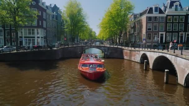 Amesterdam, Países Bajos, mayo de 2018: Un gran barco rojo con los turistas navega a lo largo del canal en Amsterdam — Vídeo de stock