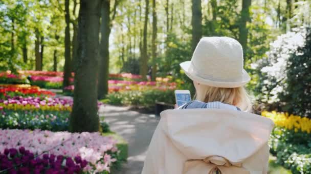 Hollanda Keukenhof parkın içinden bir smartphone onun elinde olan bir kadın elini kolunu sallaya dönüyor — Stok video