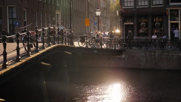 Amesterdam, Pays-Bas, mai 2018 : Beau coucher de soleil dans la ville. Eblouissement solaire dans l'eau, vélos garés sur le canal près du coffeeshop — Video