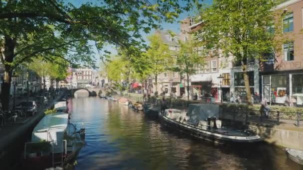 Amesterdam, Países Bajos, mayo de 2018: Bonita vista del canal en Ámsterdam. En las orillas de los barcos del canal están amarrados. Tiempo antes del atardecer — Vídeos de Stock