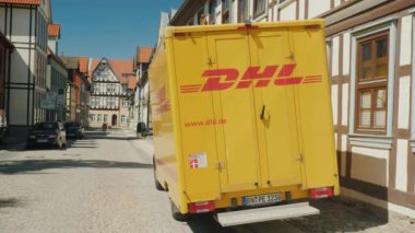 Wernigerode, Almanya, Mayıs 2018: Almanya için tipik bir mimari arka plan üzerine bir Alman kasabasında sakin bir sokakta Dhl posta servisi vagon duruyor. Arkadan Görünüş