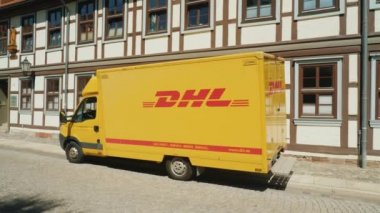 Wernigerode, Almanya, Mayıs 2018: Almanya için tipik bir mimari arka plan üzerine bir Alman kasabasında sakin bir sokakta Dhl posta servisi vagon duruyor. Yan görünüm