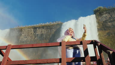 Turist kendini Niagara Falls arka planı fotoğraflar. Şelale dibinde tahta bir platformda ayakta