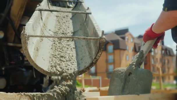 Строим коттедж. Рабочие берут бетон из смесителя в деревянную опалубку — стоковое видео