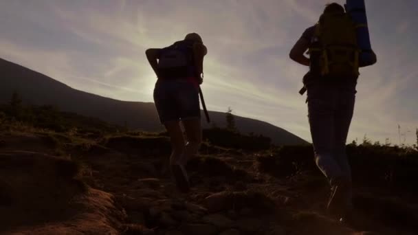 Megmásztuk a hegyet hajnalban. Két turisták felmászni a hegyi ösvényen a nap — Stock videók