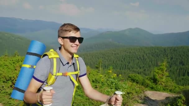 De toerist geniet van wandelen in de bergen. Het gaat gepaard met pittoreske bergen bedekt met bos — Stockvideo