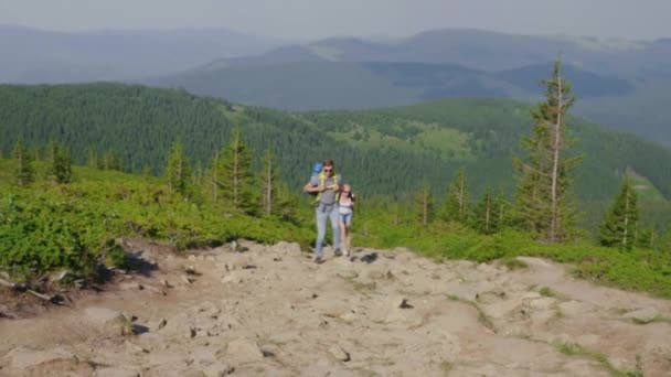 Um homem e uma mulher com mochilas rapidamente correm pelo caminho da montanha. Cargas extremas e resistência — Vídeo de Stock