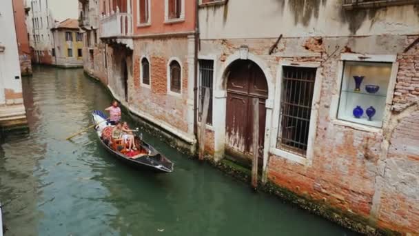 Benátky, Itálie, červen 2017: Gondola s turisty plavat v úzký kanál v centru Benátek. Tradiční architektura Benátky — Stock video