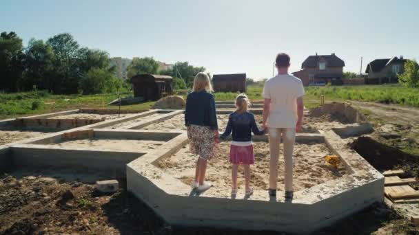 Семья находится на фундаменте своего будущего дома. Концепция новых начинаний — стоковое видео