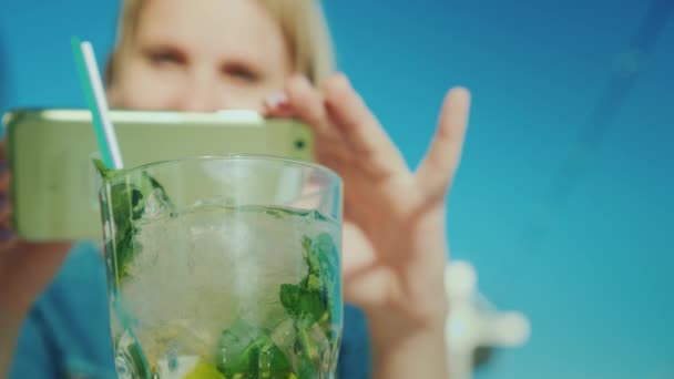 Uma blogueira está fotografando um copo com um coquetel. Crítico restaurante — Vídeo de Stock