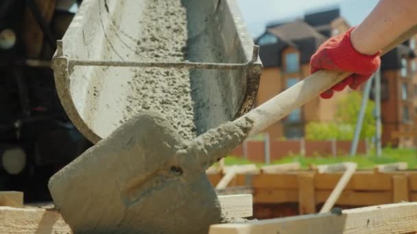 Beton aus dem Mixer in die Schalung gießen. im Hintergrund verschwommene Neubauten. Bau von Ferienhäusern Konzept — Stockvideo