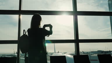 Yolculuğun keyfini çıkarın. Kadın havaalanında büyük terminal penceresi çekiyor