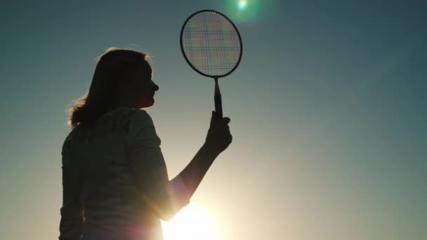 Silhuetten av medelålders kvinna med tennisracket. Aktiv sport, sommaren semester koncept — Stockvideo