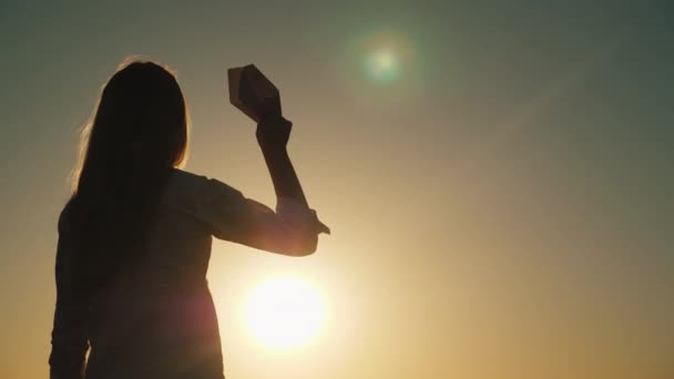 Silhouette di bambina che gioca con aeroplano giocattolo al tramonto. Bambino sogna di concetto di viaggio — Video Stock
