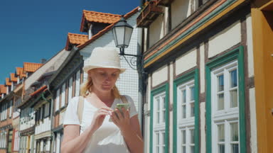 Bir turist onun elinde bir telefon ile bir Avrupa şehri güzel cadde boyunca yürüyor.