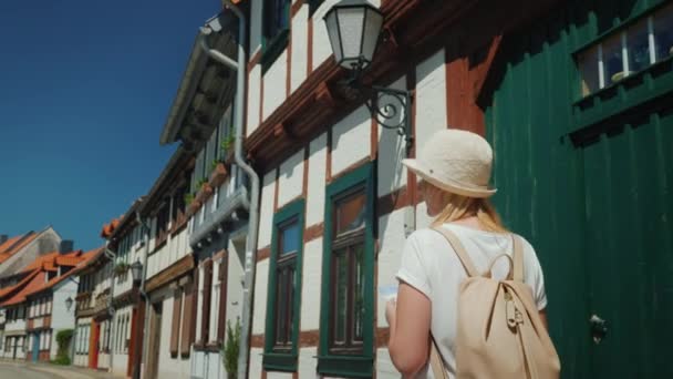 Frau mit Karte in der Hand, die auf einer malerischen Straße der deutschen Stadt spaziert. Urlaub in Europa Konzept — Stockvideo