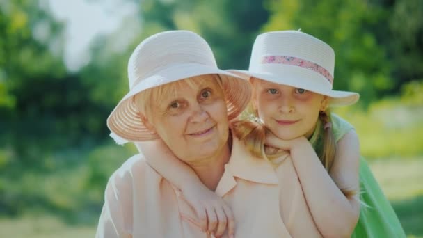 Portrait of a happy elderly woman with her granddaughter. Smiling, looking at the camera — Stock Video