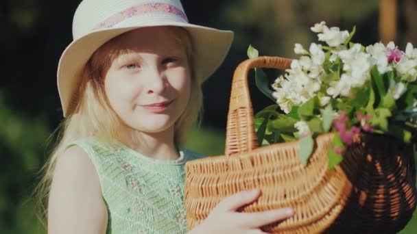 Porträtt av en ljushårig flicka på sju år med en korg med blommor — Stockvideo