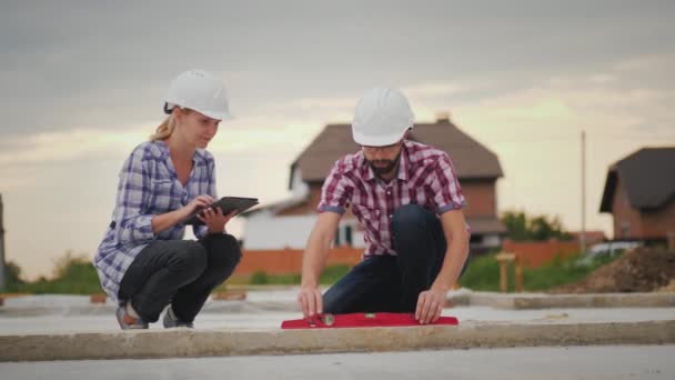 Los ingenieros verifican la precisión de la construcción del edificio. Utilice el nivel y la tableta — Vídeo de stock