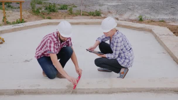Deux ingénieurs, homme et femme, vérifient l'exactitude des travaux sur le chantier. Concept de contrôle qualité — Video
