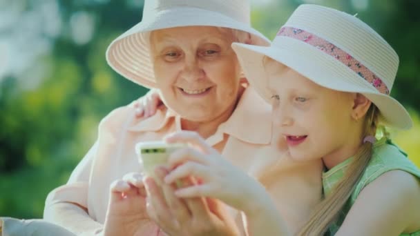 Общение поколений - бабушка с внуком играют в смартфон — стоковое видео
