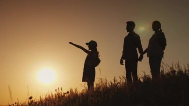 Mutlu bir aile siluetleri, onlar şafak pitoresk bir yerde buluşmak.