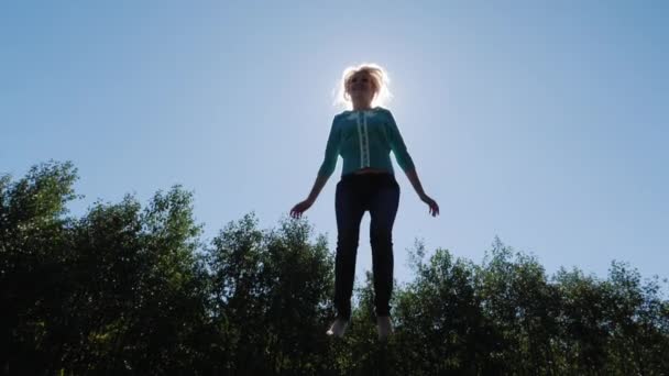 跳向太阳高。女子跳蹦床上跳高 — 图库视频影像