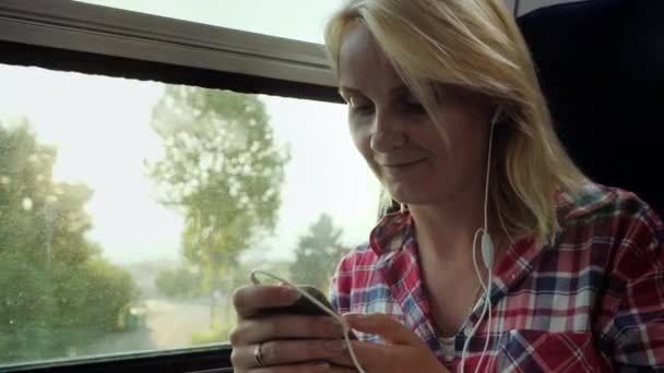 С твоим любимым устройством на дороге. Женщина путешествует на поезде, используя смартфон — стоковое видео