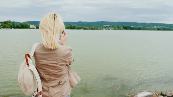 eine Frau fotografiert einen schönen See. zurück