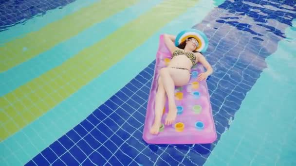 Μια ελκυστική γυναίκα είναι επιπλέουν σε ένα φουσκωτό στρώμα στην πισίνα. Γλυκό κάτω από τις ακτίνες του ήλιου. Γυναίκα έννοια παραθεριστικές κατοικίες — Αρχείο Βίντεο