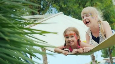Aquagrim yüzünde iki güzel kızla eğlenmek, bir hamak turistik otel toprakları üzerinde oynamak