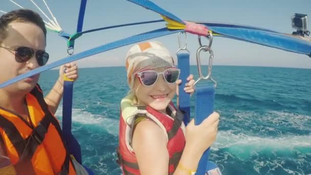 Papá y su hija están volando en parasailing. Un padre se toma una selfie con una chica, unas vacaciones activas con un niño — Vídeo de stock