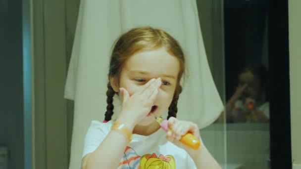 Здоровые зубы с раннего детства, маленький ребенок чистит зубы перед сном перед зеркалом в ванной комнате — стоковое видео