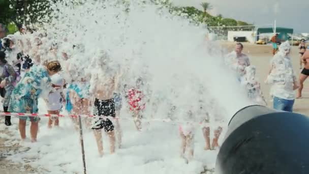 Kemer, Turchia, giugno 2018: Una folla di vacanzieri si diverte sulla spiaggia sotto i torrenti di schiuma. Festa in schiuma sulla spiaggia, animazione per turisti in Turchia — Video Stock