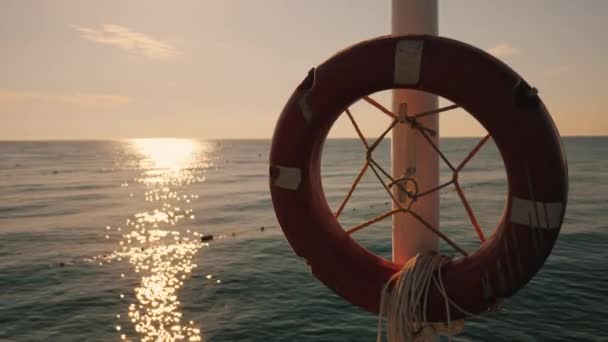 Rettungsring, der bei Sonnenaufgang im Hintergrund des Meeres hängt. Morgen am Meer — Stockvideo