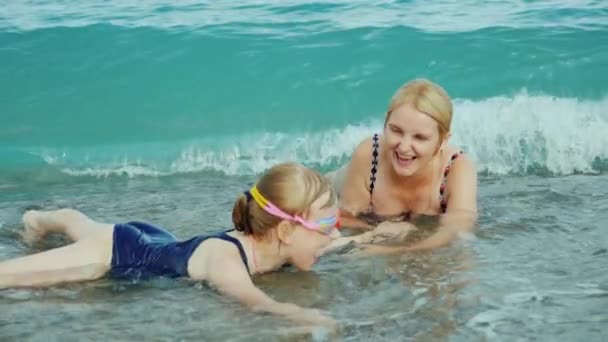 Mamá y su hija se están divirtiendo en olas de surf en el mar. Momentos felices con los niños. — Vídeos de Stock
