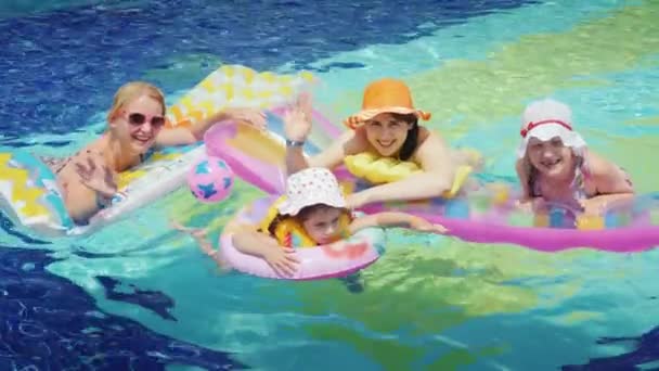 Щасливі батьки з дітьми купаються в басейні. Тримайтеся за повітряний матрац, подивіться на камеру — стокове відео