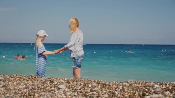 女性と彼女の娘は、サーフィンの海で楽しんでいます。波を飛び越えて楽しい — ストック動画