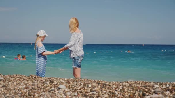 Een vrouw en haar dochter zijn plezier in de wateren van de branding. Leuk springen over de golven — Stockvideo