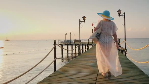 Retrovisore: Una donna in coppia e cappello cammina sul molo la mattina presto. Respira l'aria fresca . — Video Stock