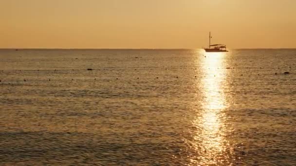 Рыбацкая лодка в море. На рассвете, красивый силуэт в блестящей тропинке на воде — стоковое видео