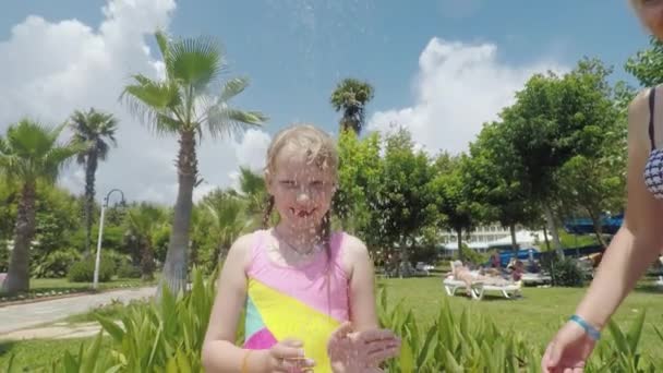 A young mother with her little daughter is having a fun shower by the pool in the seaside resort — Stockvideo