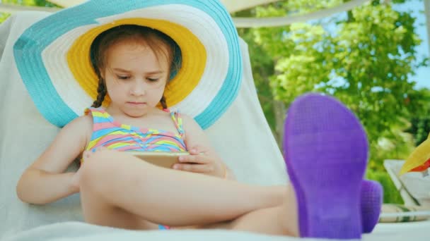 Uma mulher de negócios de férias. Senta-se em uma cadeira de praia, usa um smartphone — Vídeo de Stock