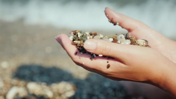 Las manos femeninas sostienen un puñado de guijarros húmedos. Descanso en el mar, concepto de meditación — Vídeos de Stock