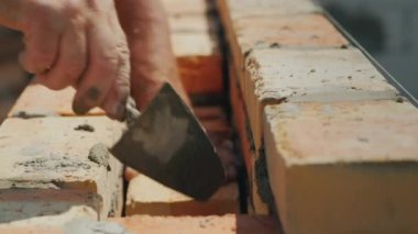 Vasıflı işçi bir tuğla duvar duvar yılında koyar. İnşaat alanında el ile çalışma