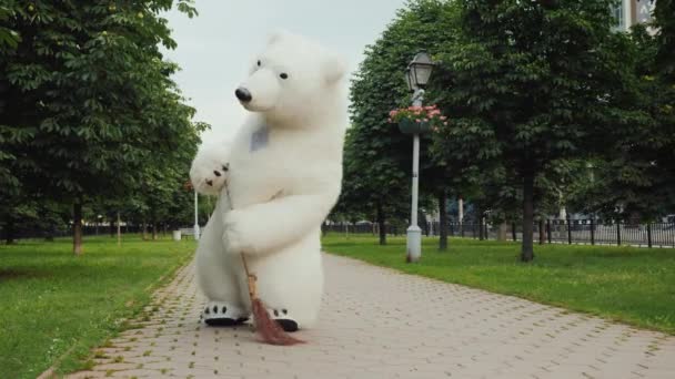 Un limpiador de osos barre la calle. Él sostiene una escoba en sus patas. Limpieza en el concepto de ciudad — Vídeo de stock