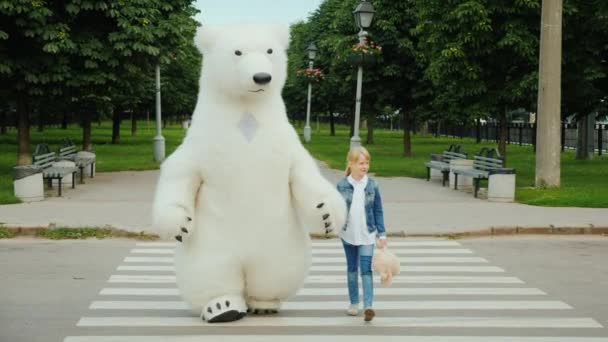 The girl takes over the paw on the pedestrian crossing of a large polar bear. Safety driving concept — Stock Video