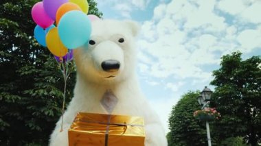 Serin bir kutup ayısı şehrin sokak yürüyor, bir hediye taşıyan ve belgili tanımlık paws balonlar
